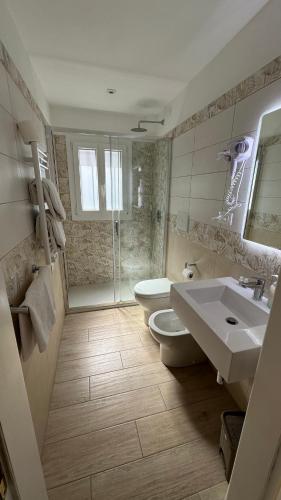 a bathroom with two sinks and a toilet and a shower at Hotel Giardino del Sole in Savona