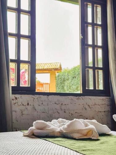 a blanket laying on a bed in front of an open window at Pousada All Green - Monte Verde in Monte Verde