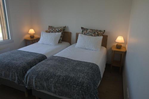 two beds in a room with two lamps on tables at LE DOMAINE DES SENS - Chalet avec SPA privatif - pleine nature - expérience détente in Hans