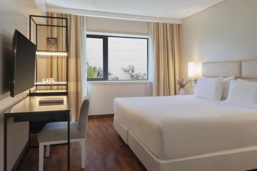 a hotel room with a bed and a desk with a computer at NH Mendoza Cordillera in Mendoza