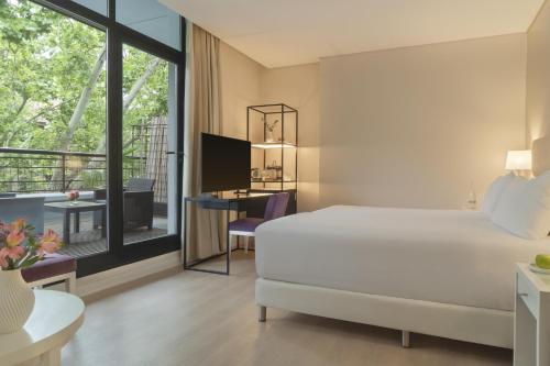 a hotel room with a bed and a desk and a window at NH Mendoza Cordillera in Mendoza