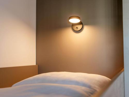 a light on a wall next to a bed at B&B HOTEL Rostock-Hbf in Rostock