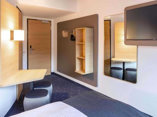 a room with a bed and a desk and a tv at B&B HOTEL Rostock-Hbf in Rostock