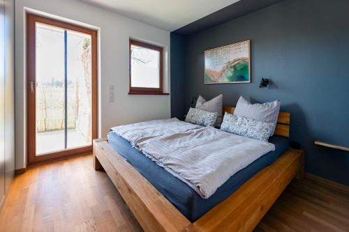 a bedroom with a large bed with a blue wall at BergSeeMomente in Breitbrunn am Chiemsee