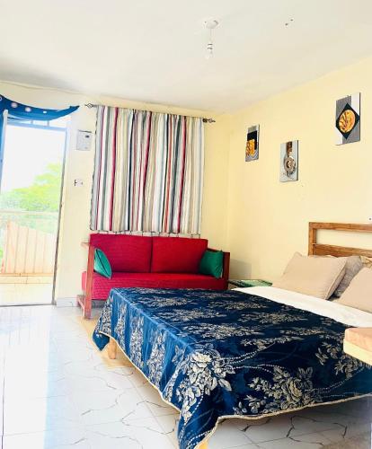 a bedroom with a bed and a red couch at Zion Homes in Taveta
