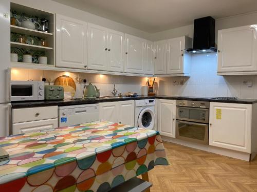 a kitchen with white cabinets and a table in it at Hidden Gem in a great location very near Isle of Skye in Kyle of Lochalsh