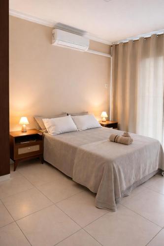 a bedroom with a bed with two night stands and two lamps at Apê 401 - Central, Garagem e Ar-Condicionado - 2Q in Governador Valadares