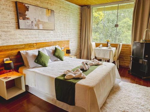 a bedroom with a large bed with towels on it at Pousada All Green - Monte Verde in Monte Verde