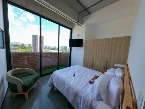 a bedroom with a bed and a chair and a large window at Atom Cuatro 303 in Guatemala