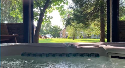 a hot tub in a house with a view of a yard at LE PRESBYTERE in Chasnay