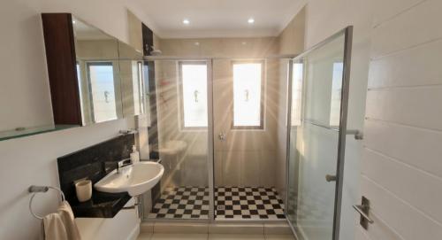 a bathroom with a sink and a shower and a toilet at Sandstone - 2 x Bedroom Apartment! in Knysna