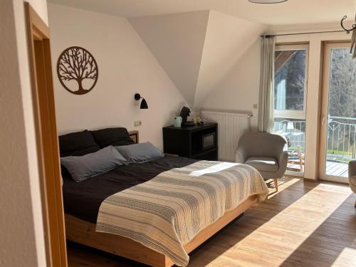 a bedroom with a bed and a chair and a window at Haus Moselliebe B&B in Ediger-Eller
