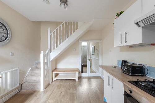 a kitchen with white cabinets and a spiral staircase at The Nook - Quaint Victorian Home With Free Parking in York
