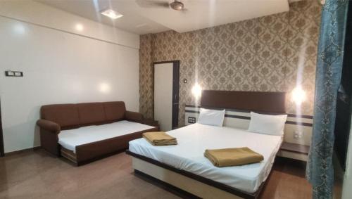 a hotel room with a bed and a couch at Hotel Shiv Sai in Shirdi