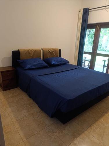 a blue bed with blue pillows in a bedroom at Golden Leaf house in Weligama