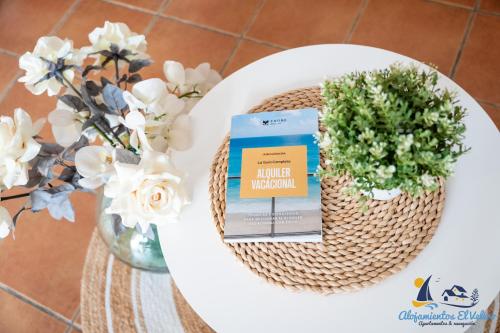 a book on a table next to a vase of flowers at El Velero - Vacaciones inolvidables frente el MAR in San José