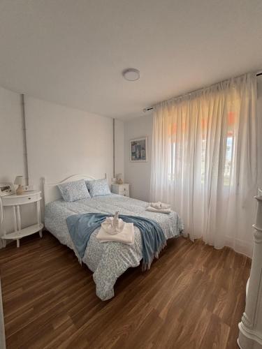 a white bedroom with a bed and a window at Torkes in Foz