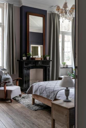 a bedroom with a bed with a mirror and a fireplace at Villa Grand Maur in Spa