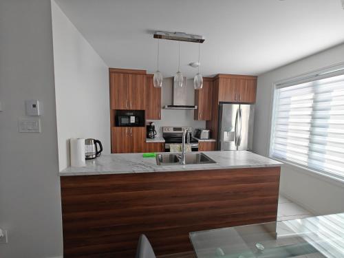 a kitchen with wooden cabinets and a stainless steel refrigerator at Appartement sur deux niveaux in Quebec City