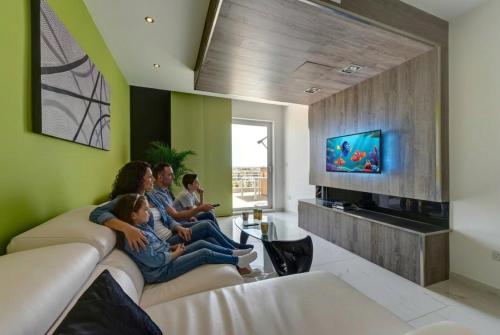 a family sitting on a couch in a living room at Apartment with Private Jacuzzi and Terrace in St Julians 3 Bedrooms in St. Julianʼs