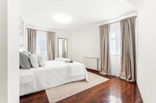 a white bedroom with a white bed and windows at Vale do Vez in Arcos de Valdevez