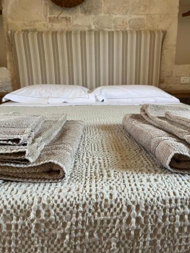 a bed with two blankets on top of it at Masseria Morrone in Ostuni