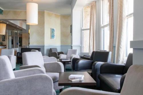 a waiting room with chairs and tables and windows at The Beresford Hotel in Newquay