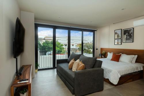 a bedroom with a bed and a couch and a tv at Cozy Americana Condo GDL in Guadalajara