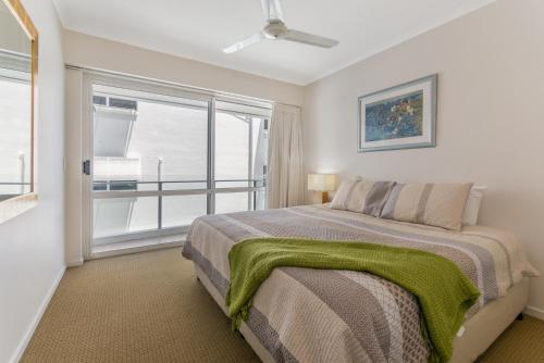 a bedroom with a bed and a large window at Bali Hai Apartments Noosa in Noosa Heads