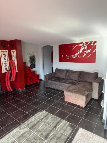 Una sala de estar con un sofá y una pared roja. en L'Estel, en Hasparren