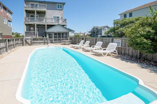 a swimming pool with lounge chairs and a house at Funtiki - S Nags Head MP 17.5, Semi-Oceanfront, 150 Yds to Beach, Pool, Hot Tub, Pool Table, Pets OK in Whalebone