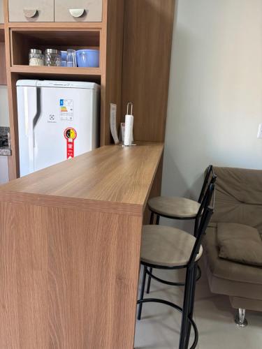 a kitchen with a counter with a refrigerator and two stools at Studio J&C in Primavera do Leste