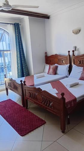 a room with three beds and a window at Palm Comfort Apartment in Bamburi