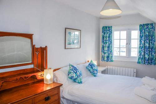 a bedroom with a bed with a dresser and a mirror at Waders in Salcombe