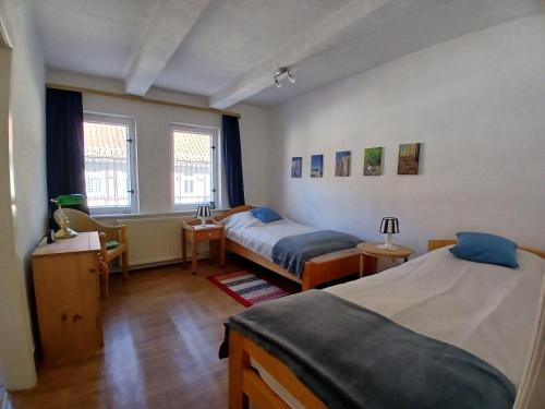 a bedroom with two beds and a desk and two windows at Ferienhaus-Juliana in Stolberg
