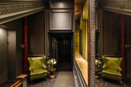 a hallway with green chairs and a mirror at The William Hotel Midtown, New York in New York