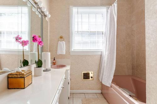 ein Badezimmer mit einer rosa Badewanne, einem Waschbecken und einem Spiegel in der Unterkunft Ida's Oasis in Pine Bluff