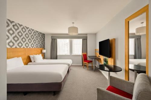 a hotel room with two beds and a tv at Holiday Inn Newcastle-Jesmond by IHG in Newcastle upon Tyne