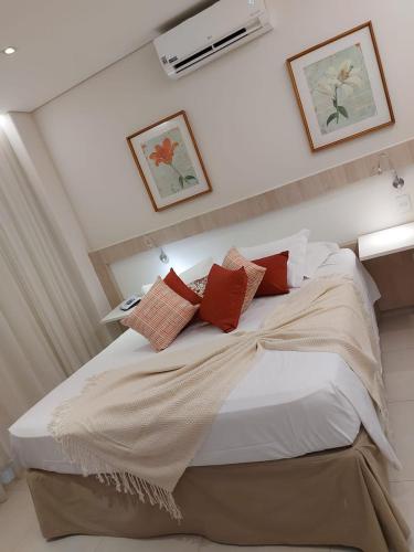 a bedroom with a large bed with red pillows at Lirio D'Água Hotel in Olímpia