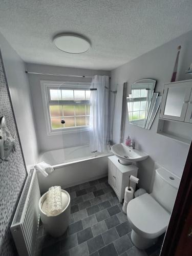 a bathroom with a tub and a toilet and a sink at Sunshine Lodge Haven Lakeland in Flookburgh
