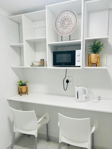 a kitchen with white chairs and a counter with a microwave at Duvha Guesthouse in Graskop