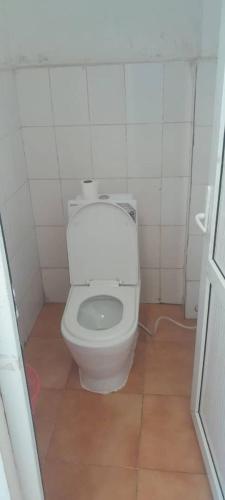 a bathroom with a toilet in a white tiled room at Birhanu Guest House and Tours in Lalibela