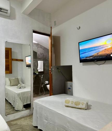 a bedroom with two beds and a flat screen tv on the wall at Pousada Zoom Jericoacoara in Jericoacoara