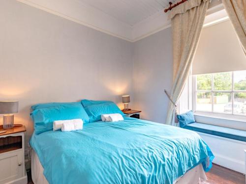 a blue bedroom with a bed and a window at 2 Bed in Holt oc-ncc66 in Blakeney
