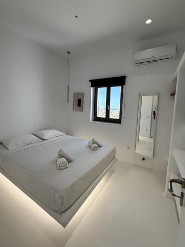 a white bedroom with a bed and a window at Sunwave Mykonos Villa in Mykonos