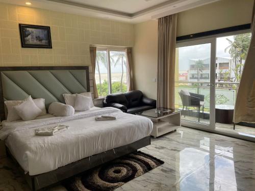 a bedroom with a large bed and a balcony at Aryans Sea Sight Resort Mandarmani in Mandarmoni