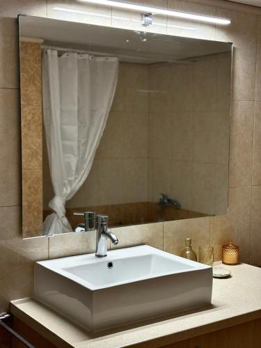 a bathroom with a sink and a large mirror at Olea House in Elia Laconias