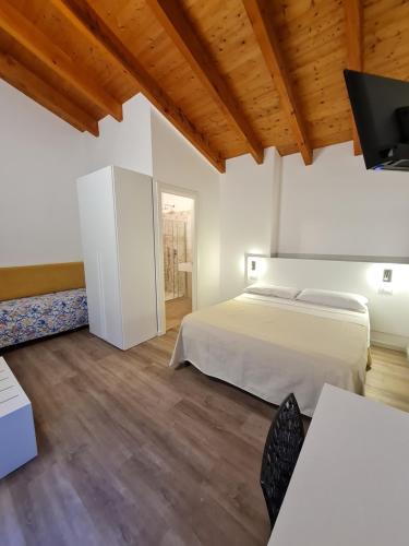 a bedroom with a bed and a tv and wooden ceilings at Hotel Giardino del Sole in Savona