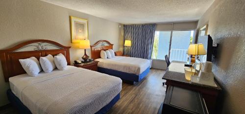 a hotel room with two beds and a balcony at Days Inn by Wyndham Orlando Downtown in Orlando