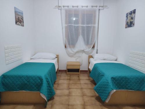 two beds in a room with green sheets at Tropea's green terrace in Tropea